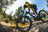 Mountainbiker fährt über einen felsigen Waldtrail bei sonnigem Wetter